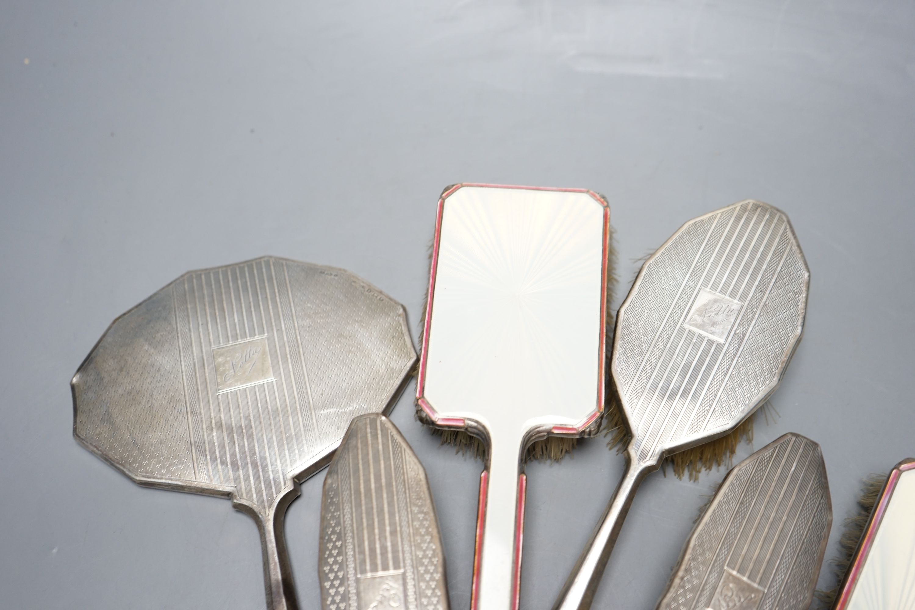 Two 1950's silver and enamel mounted brushes and an earlier four piece silver mounted brush set.